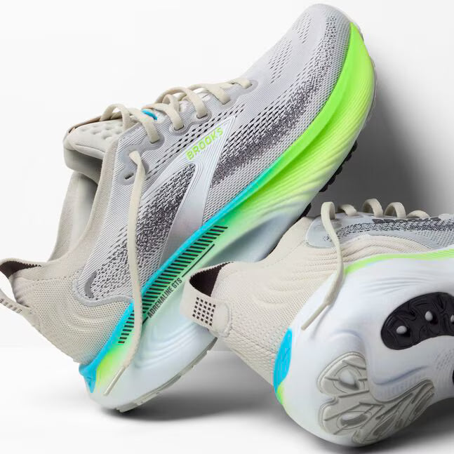 Gray and white running shoes with green and blue accents on a light gray background