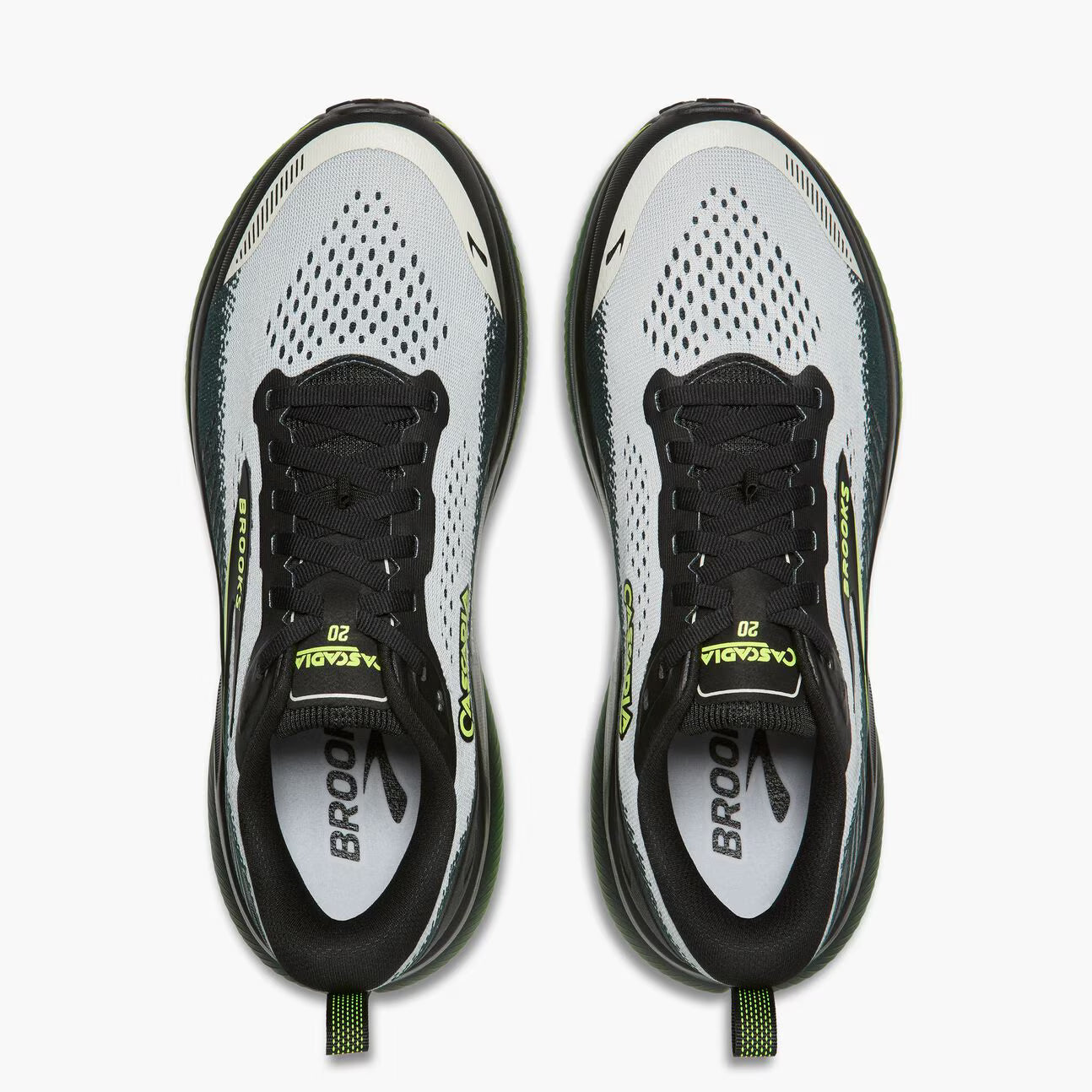 A pair of Brooks Cascadia 20 running shoes shown from a top-down view against a clean white background. The shoes feature a white and gray mesh upper with black overlays, black laces, and bright neon yellow-green accents on the tongue, heel, and pull tabs.