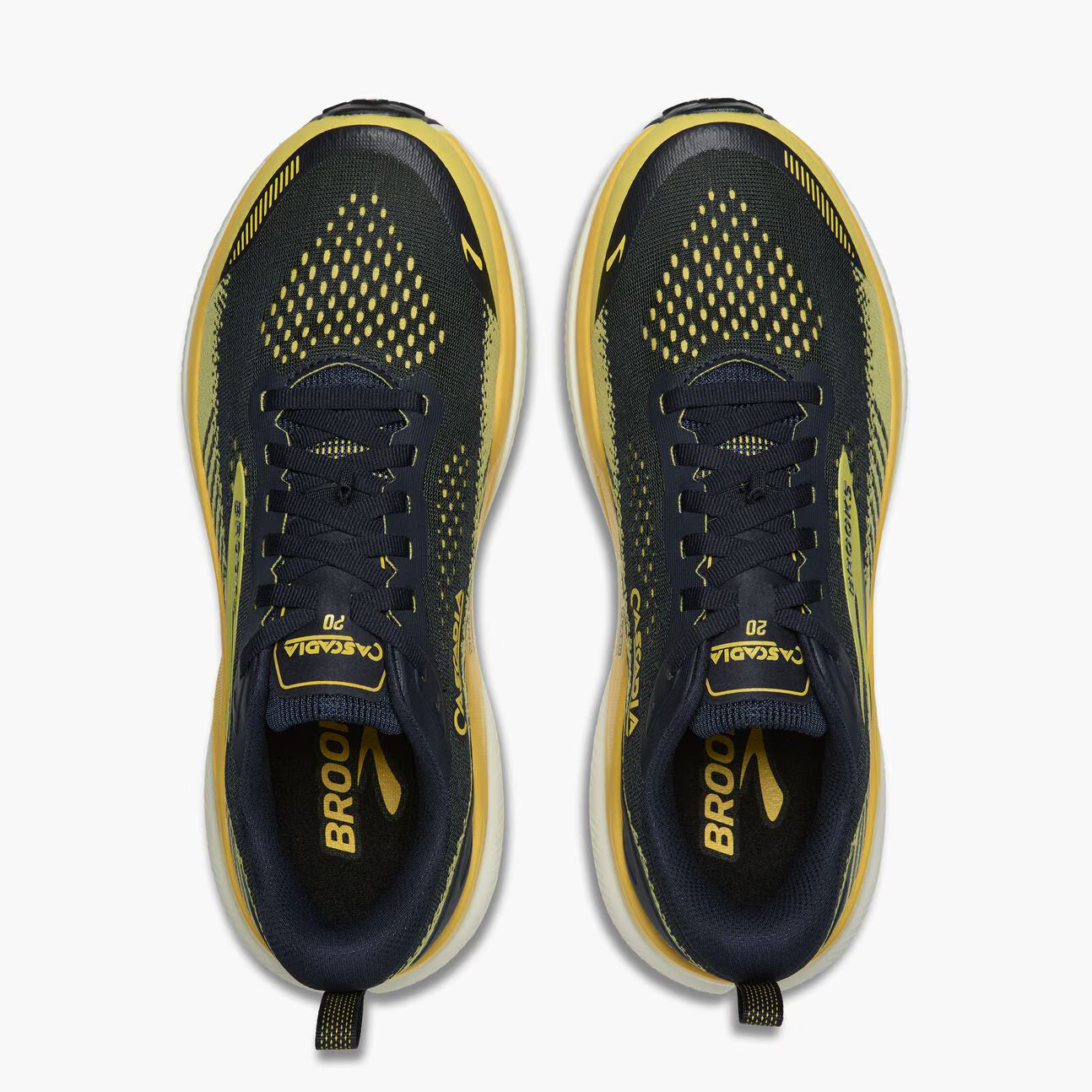 A pair of Brooks Cascadia 20 running shoes shown from a top-down view, featuring a dark navy blue and yellow mesh upper with a thick white midsole.