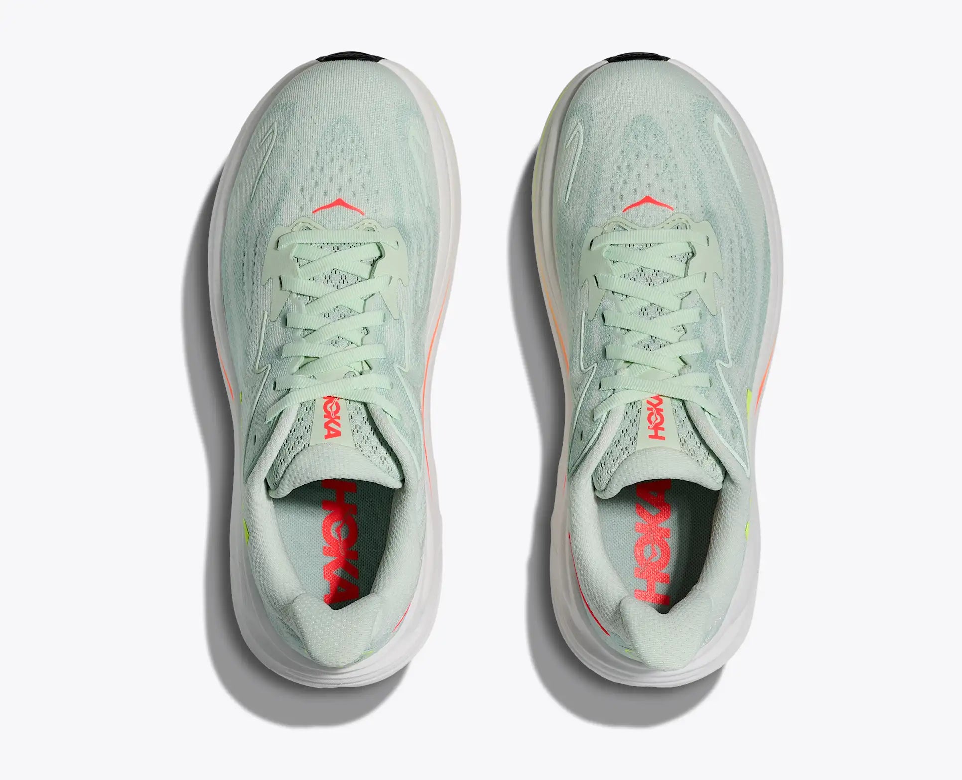 Pair of light green running shoes with red accents on a white background