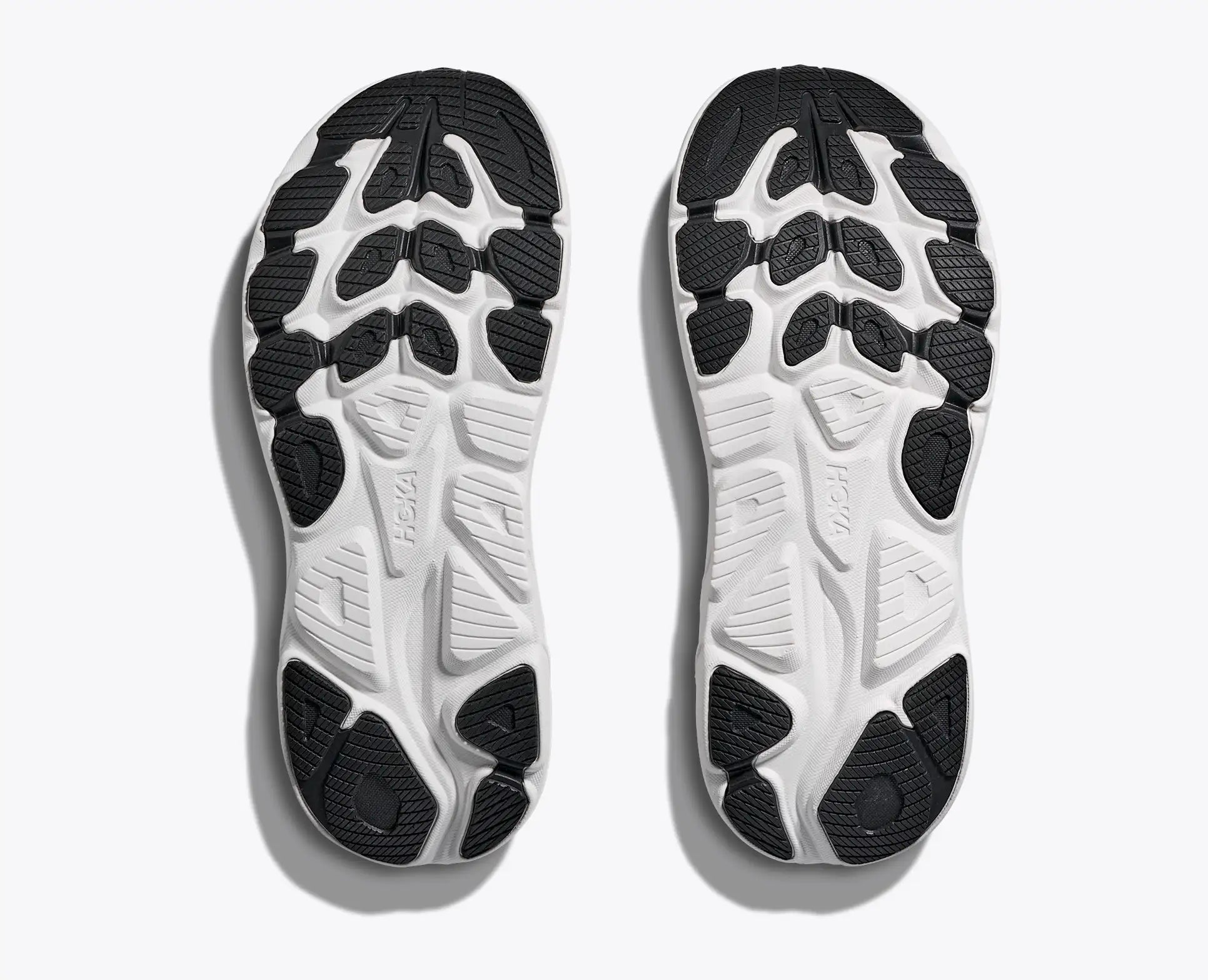 Close-up of a pair of white athletic shoes with black sole pattern on a light gray background