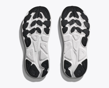 Close-up of a pair of white athletic shoes with black sole pattern on a light gray background