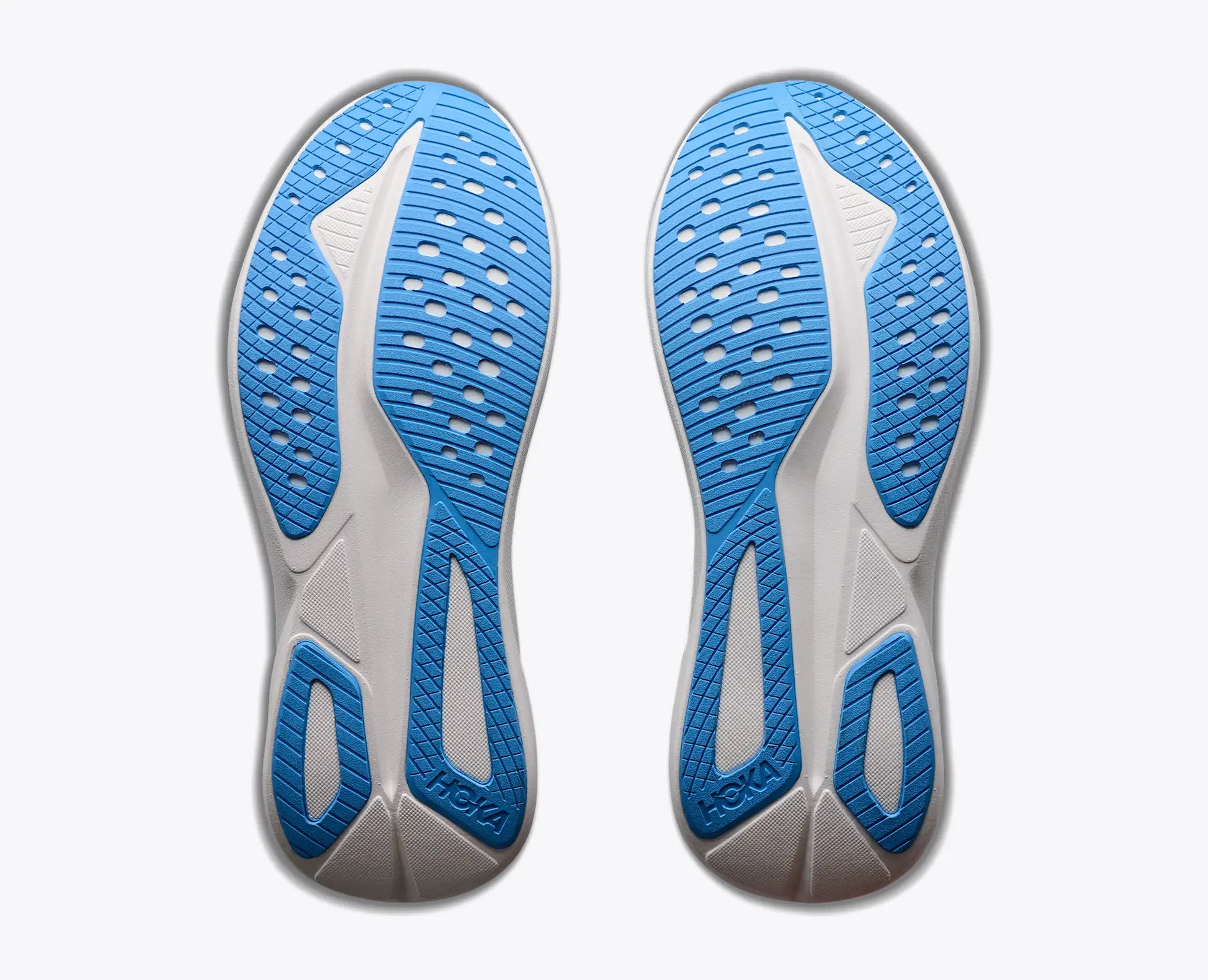 The outsoles of a pair of Hoka Mach 7  running shoes, showing the textured blue and white tread pattern against a light gray background.