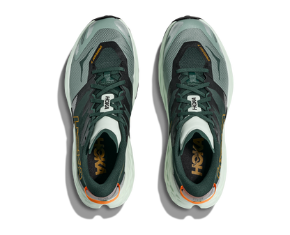 Pair of green athletic shoes with orange accents on a white background