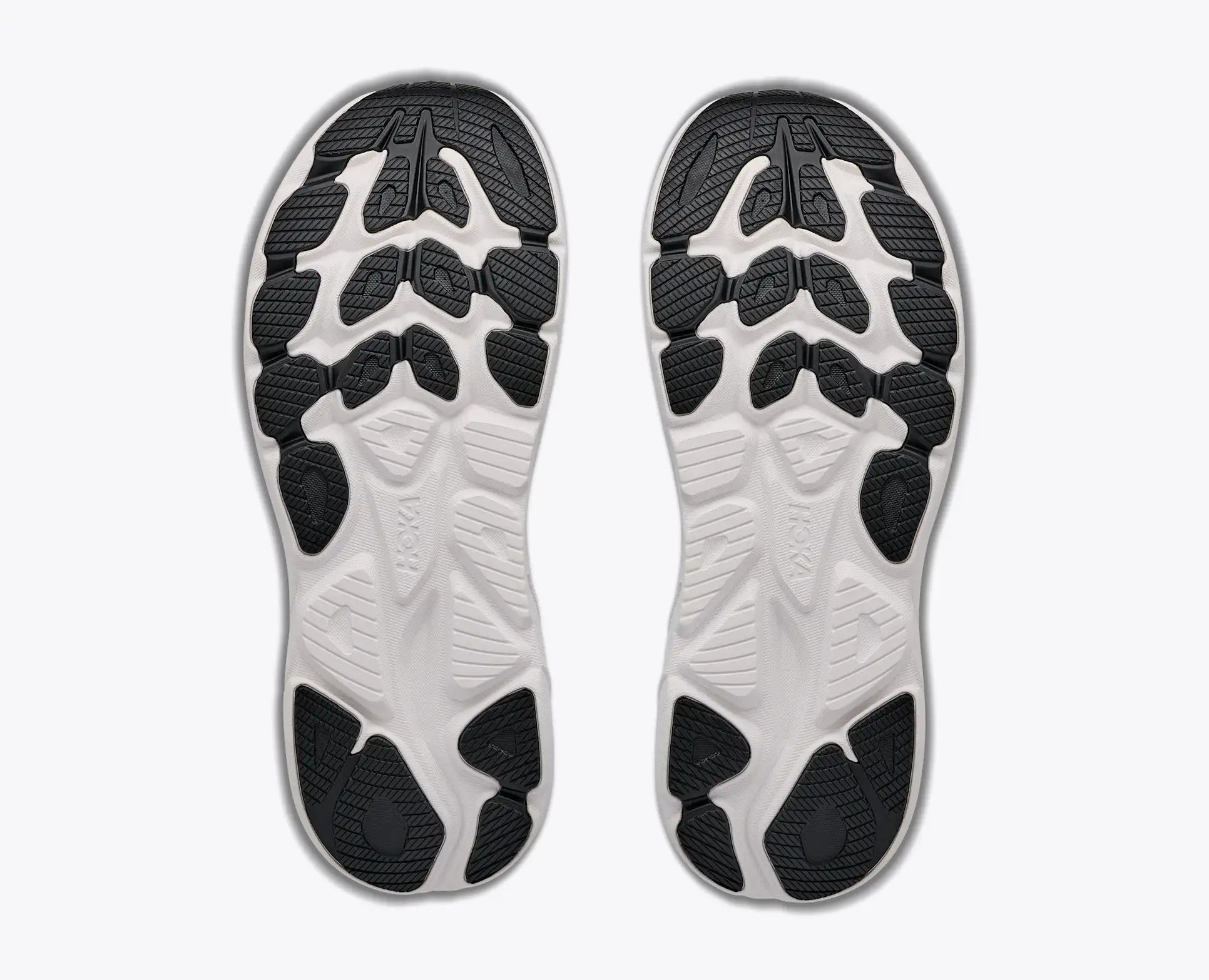 Close-up of white Hoka Men's Clifton 11 athletic shoes with black sole pattern on a white background