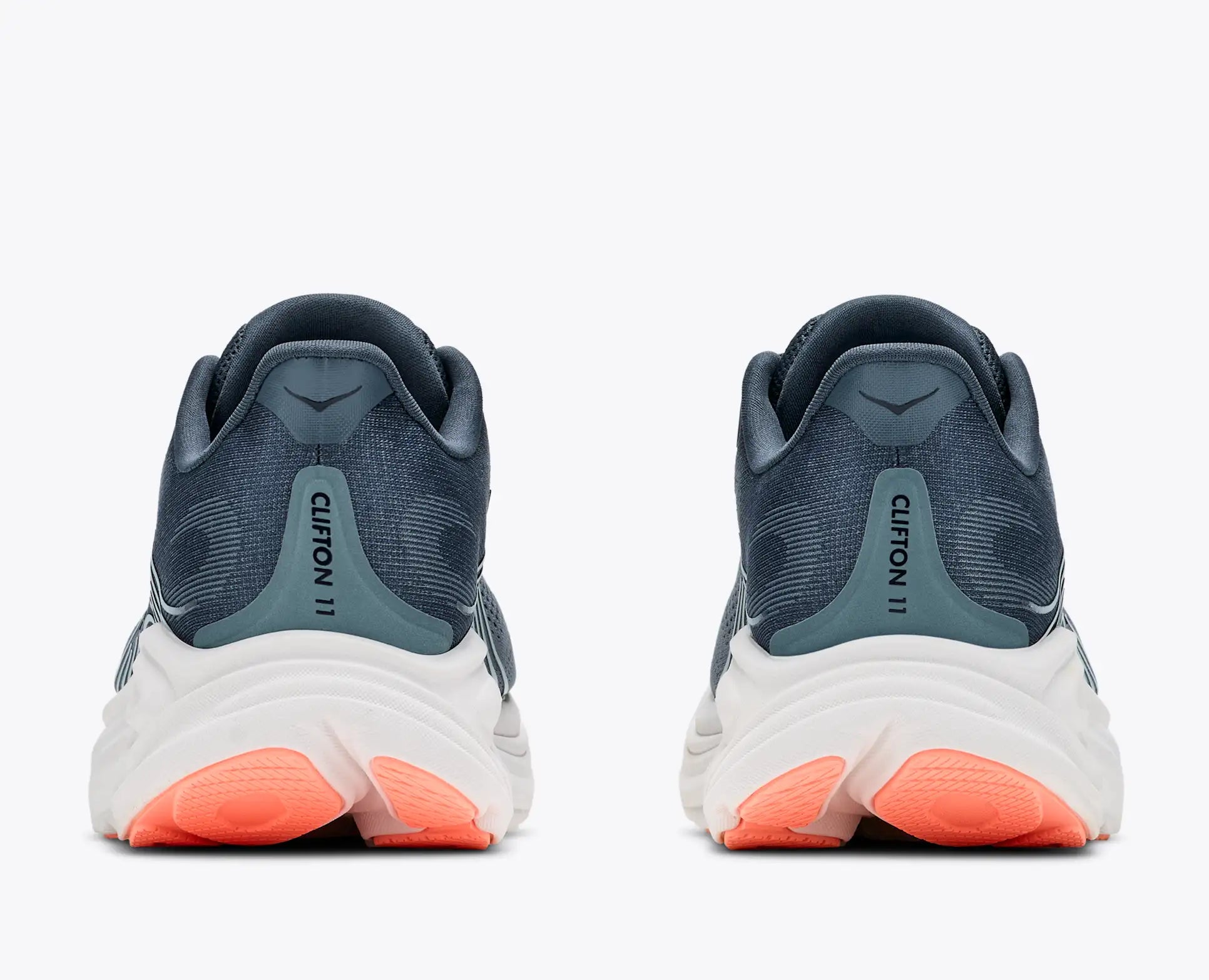 A pair of running shoes shown from the rear, featuring a dark slate blue and teal upper, a thick white midsole, and bright coral orange outsoles, on a light gray background.