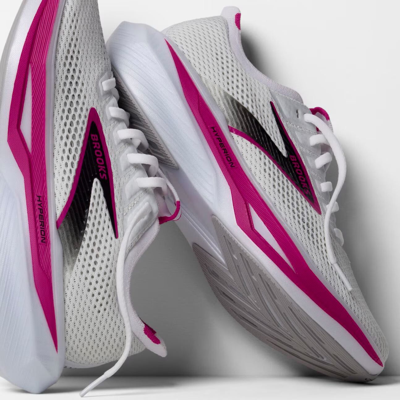 White and pink running shoes with visible branding on a light gray background