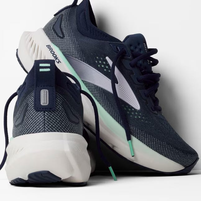 Navy and white running shoes with green accents on a light gray background