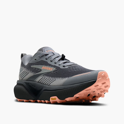 Brooks trail running shoe in dark gray and black with a coral pink outsole, shown from a three-quarters angle on a light gray background.