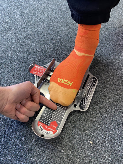 Foot with orange Hoka sock in a brannock device 