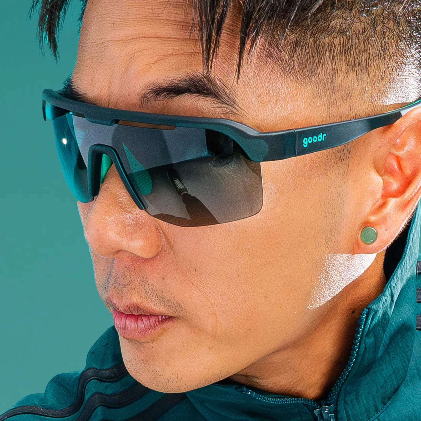Person wearing Goodr Bolt G: Electric Zen Machine teal sunglasses with 'goodr' branding against a teal background