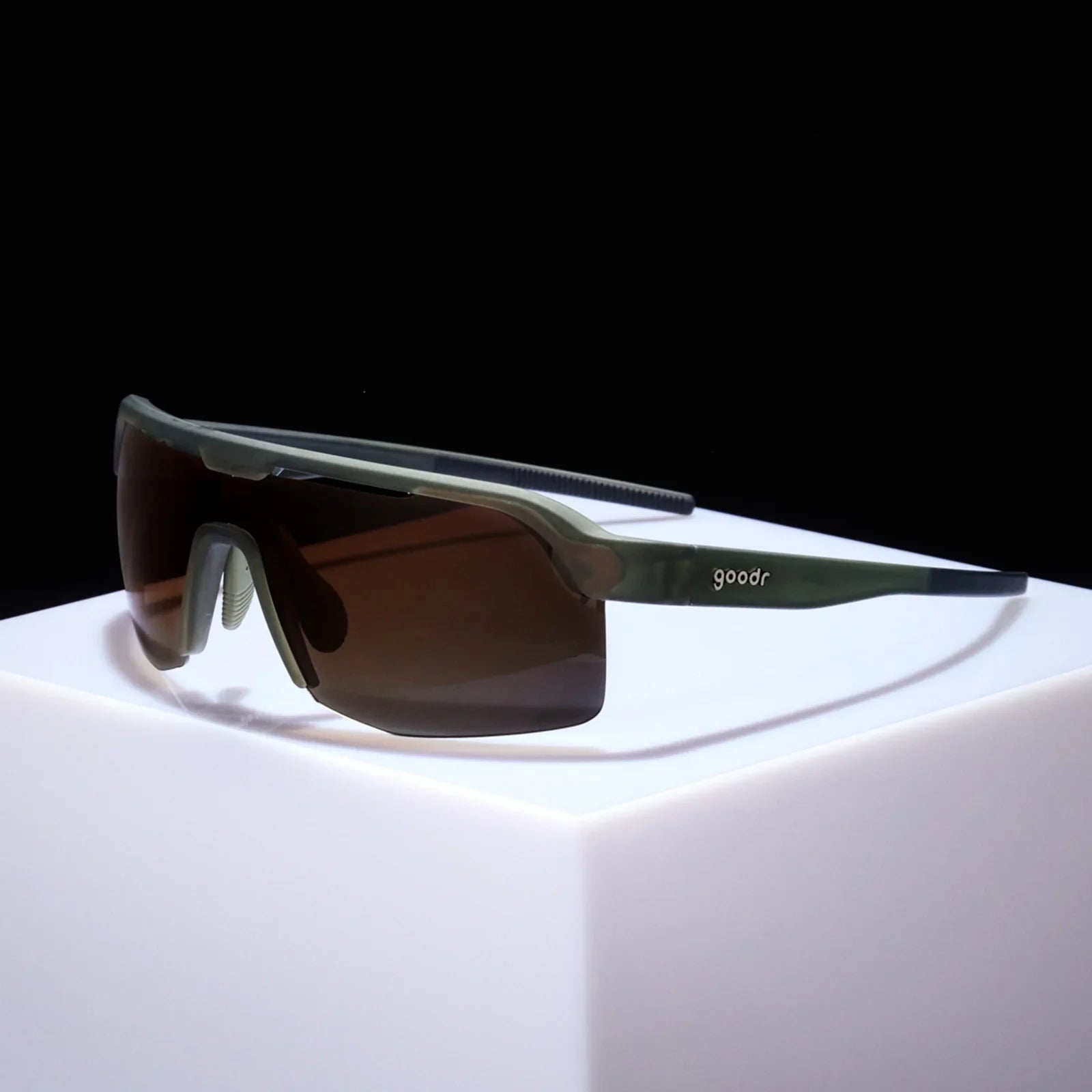 Goodr Bolt G The Jungle Is My Gym Sunglasses with a dark frame and brown lenses on a white surface with a black background