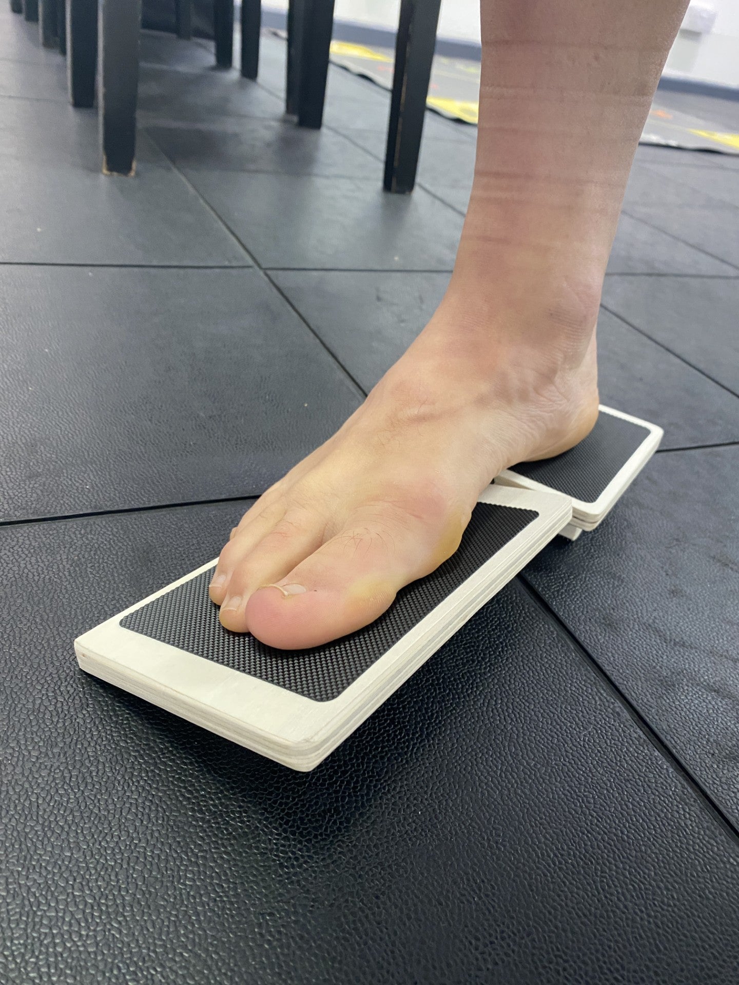 Person using a foot mobility device on a black floor.