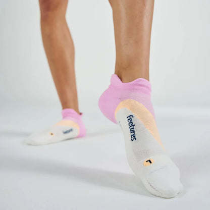 Person wearing pink and gray ankle socks with 'feetures' branding on a light background