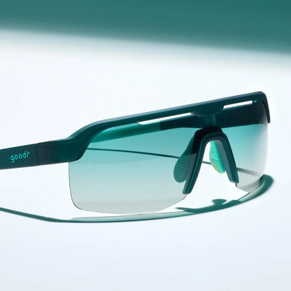 Goodr Bolt G: Electric Zen Machine Teal sunglasses with a clear lens on a light gray background