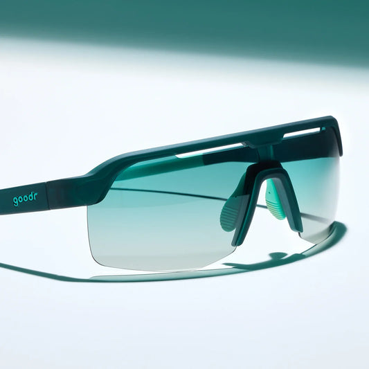 Goodr Bolt G: Electric Zen Machine Teal sunglasses with a clear lens on a light gray background