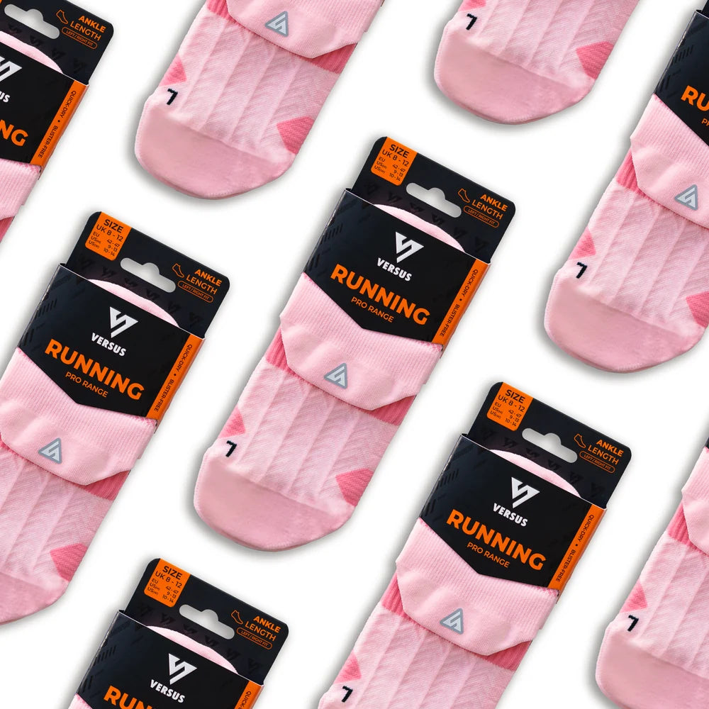 Pink ribbed running socks with a small white triangle logo, shown in multiple pairs on black and orange retail cards against a white background.