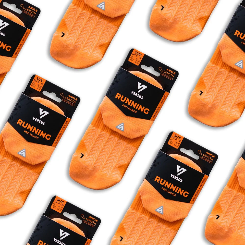 Multiple pairs of orange running socks with black packaging on a white background