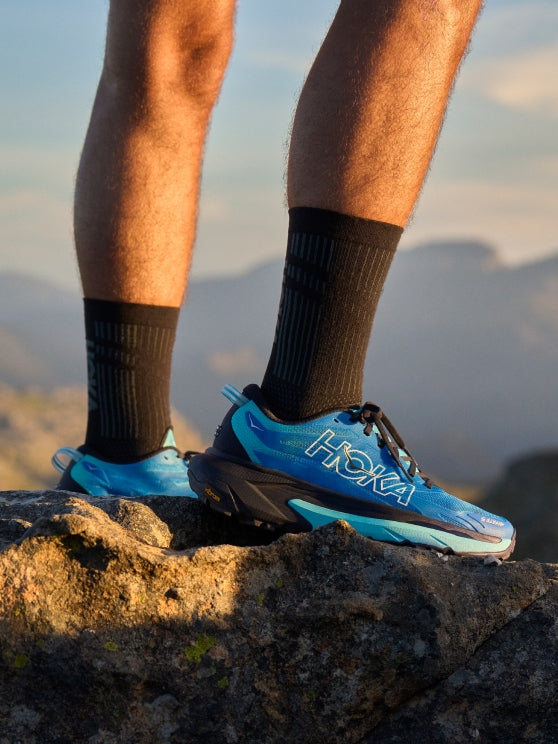 Person wearing blue Hoka running shoes on a mountainous landscape