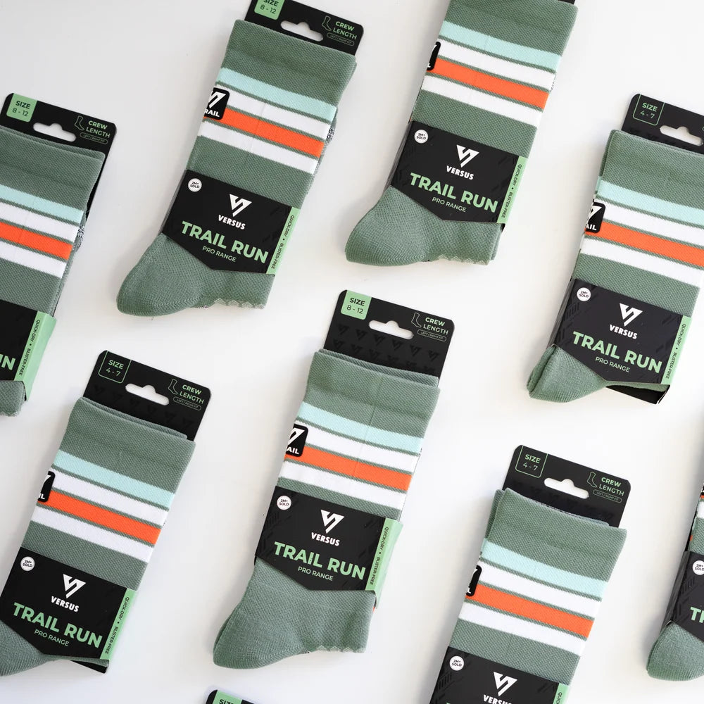Multiple pairs of green and orange striped socks with 'Trail Run' label on a white background