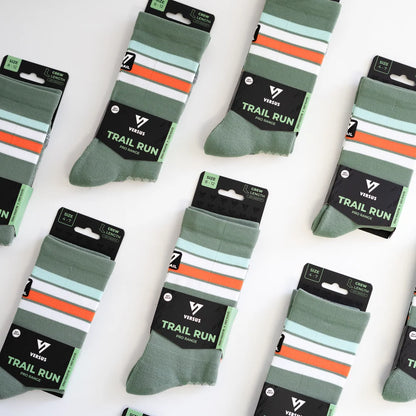 Multiple pairs of green and orange striped socks with 'Trail Run' label on a white background