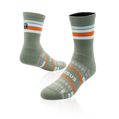 A pair of Versus Fit athletic crew socks in sage green, featuring orange and white stripes on the cuff, a honeycomb pattern on the foot, and the Versus Fit logo on the toe.