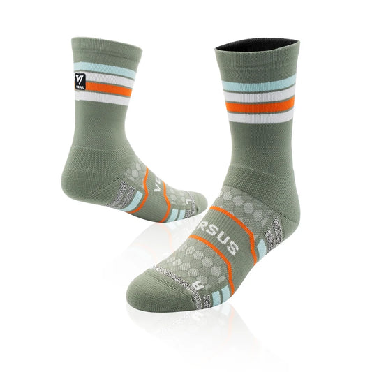 A pair of Versus Fit athletic crew socks in sage green, featuring orange and white stripes on the cuff, a honeycomb pattern on the foot, and the Versus Fit logo on the toe.